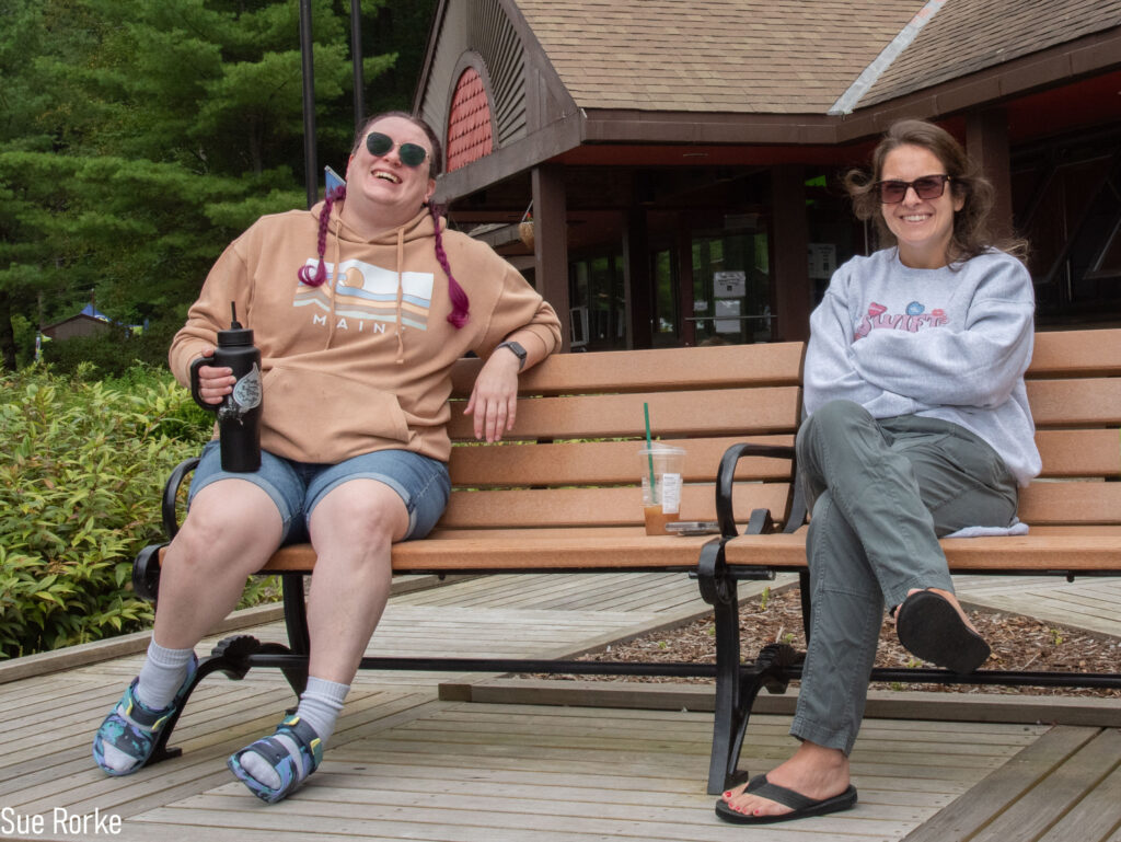 Erin and Brittney (MWCIL) sitting on a bench smiling