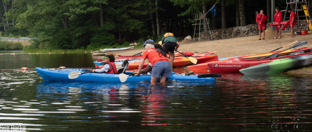Staff help people into kayaks