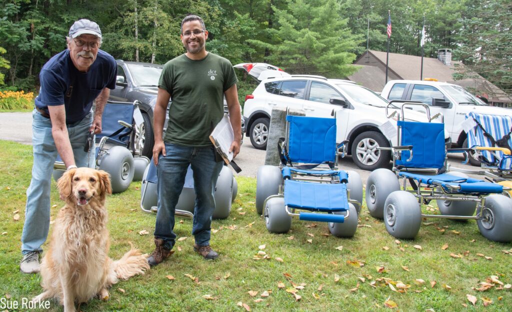 DCR staff and man with dog in front of beach wheelchairs