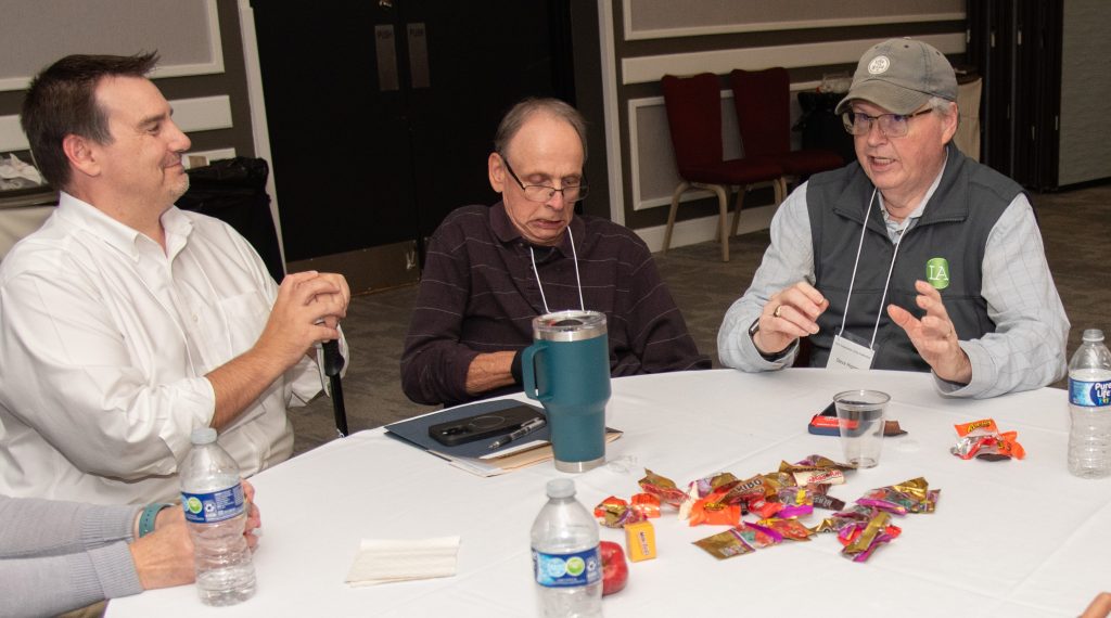 3 men talking, including Steve Higgins and Mike Kennedy