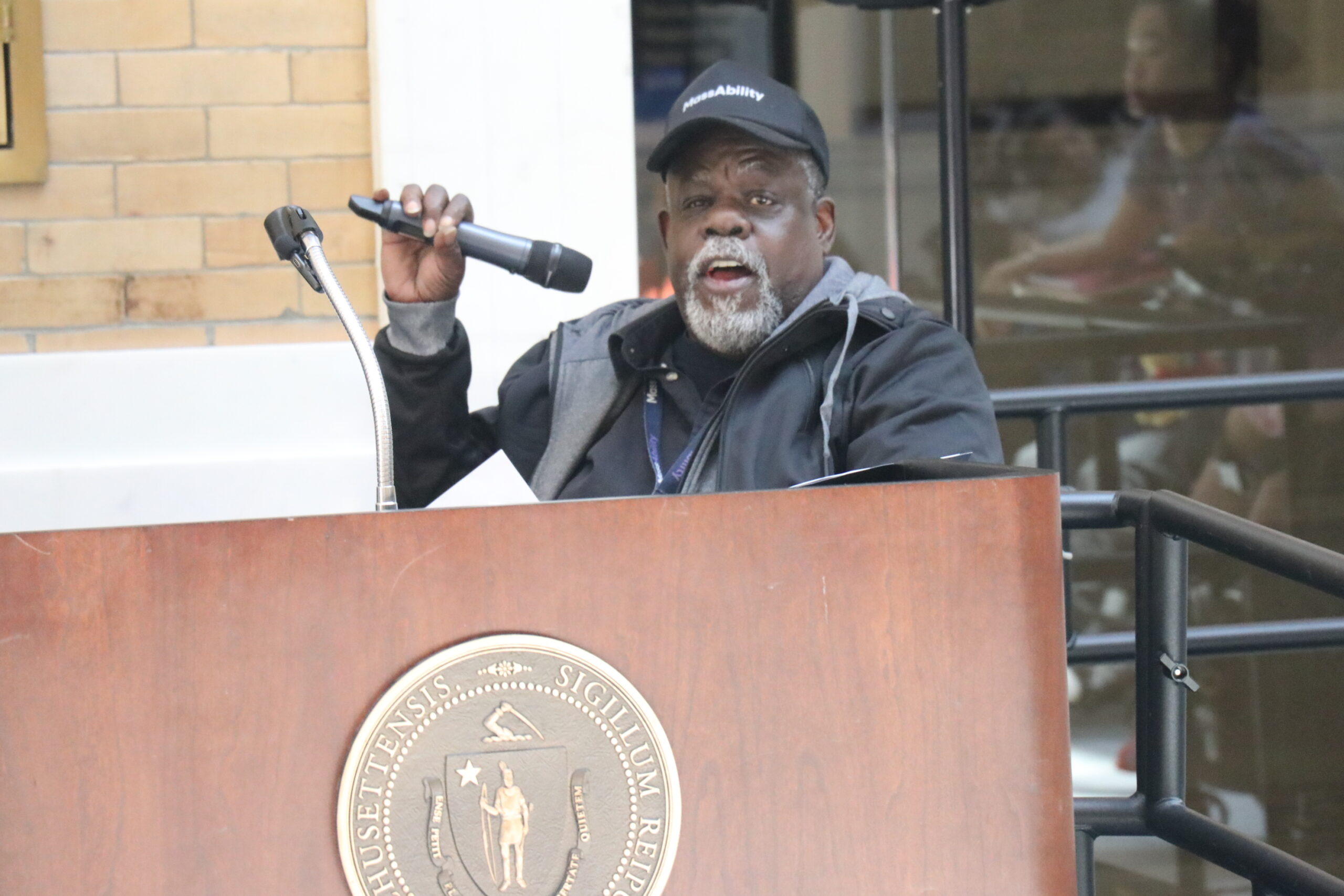 James McKenzie holding a microphone and speaking at a podium 