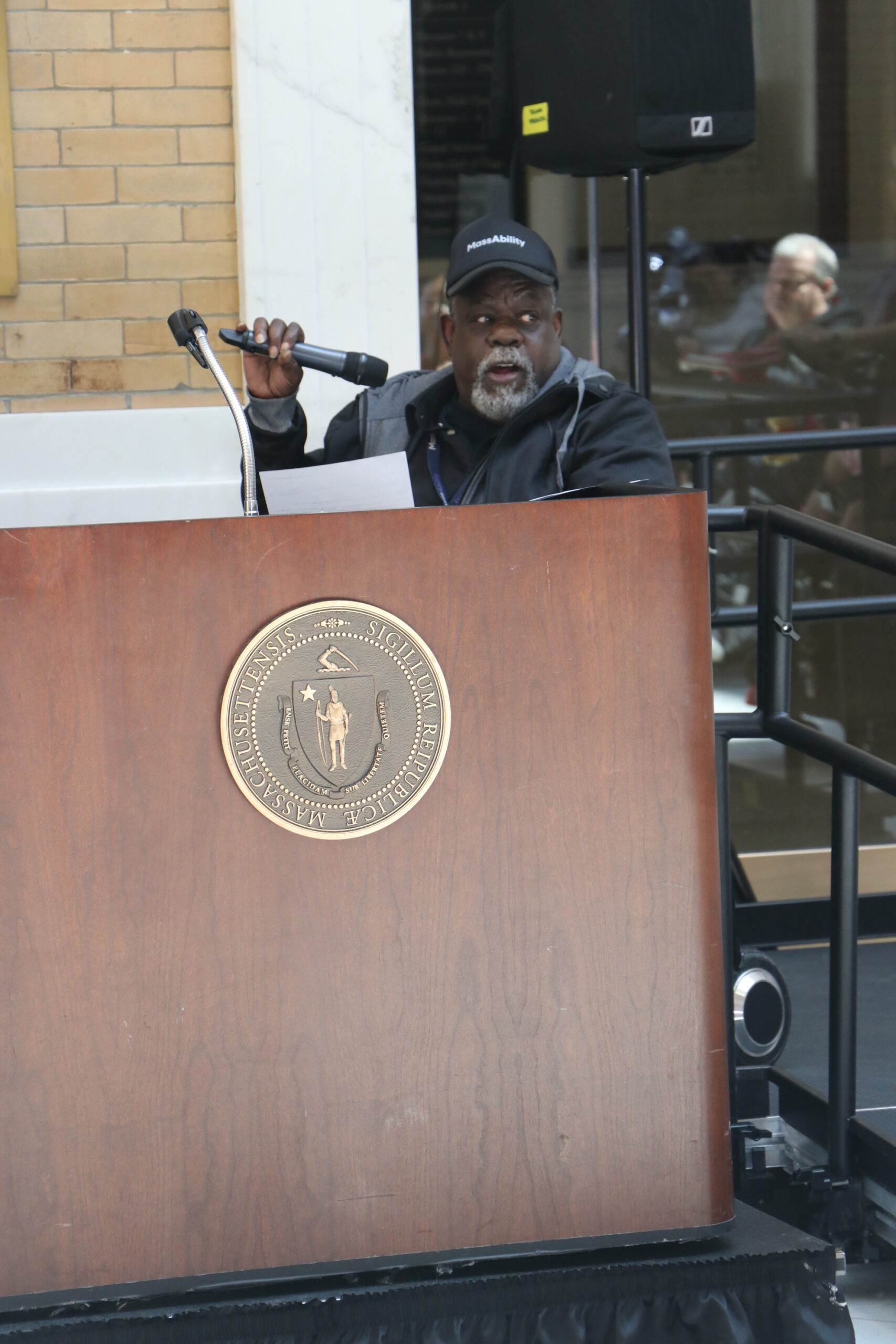 James Mckenzie speaking with a microphone at a podium 
