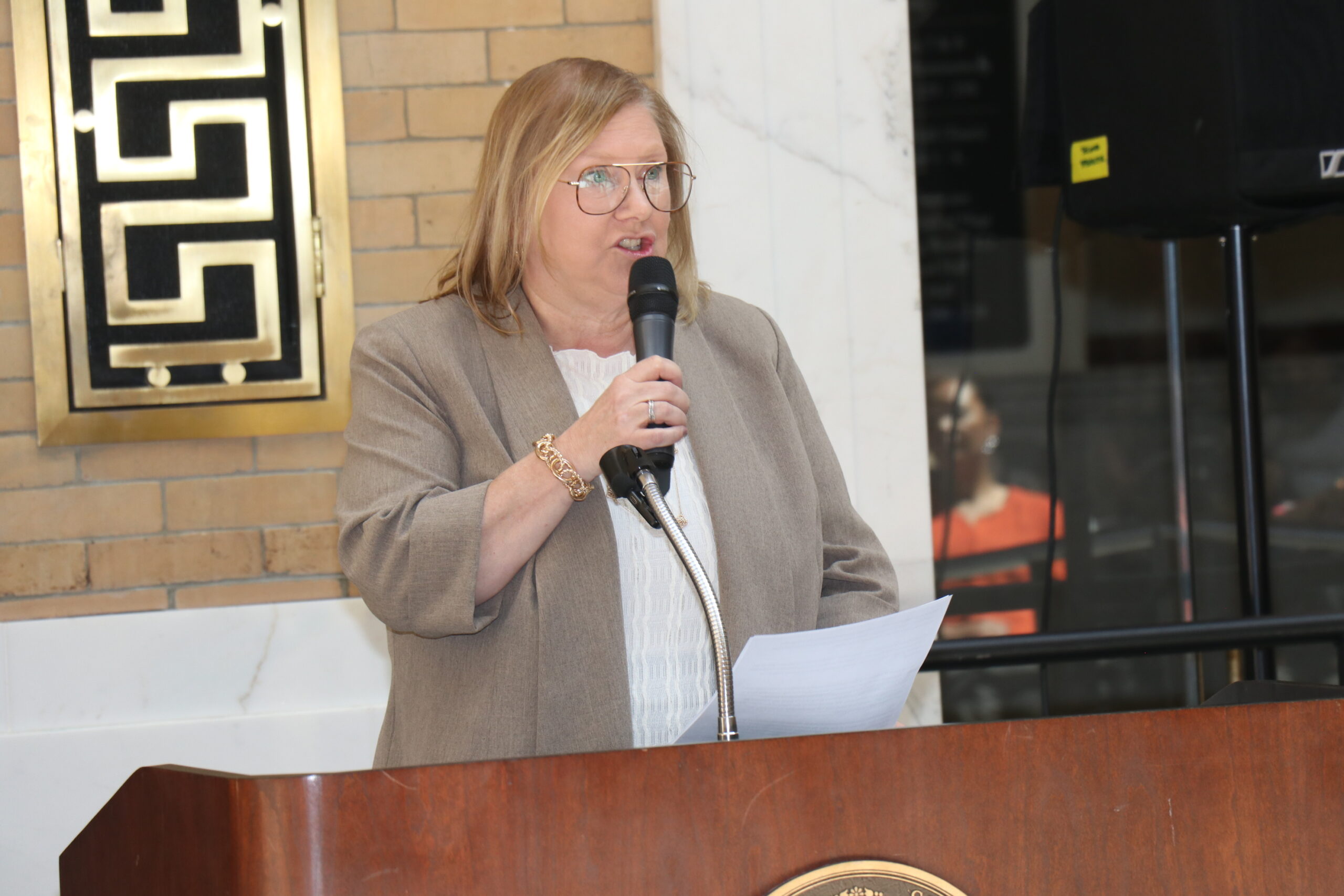 Jessica Cimini speaking with a microphone at a podium 