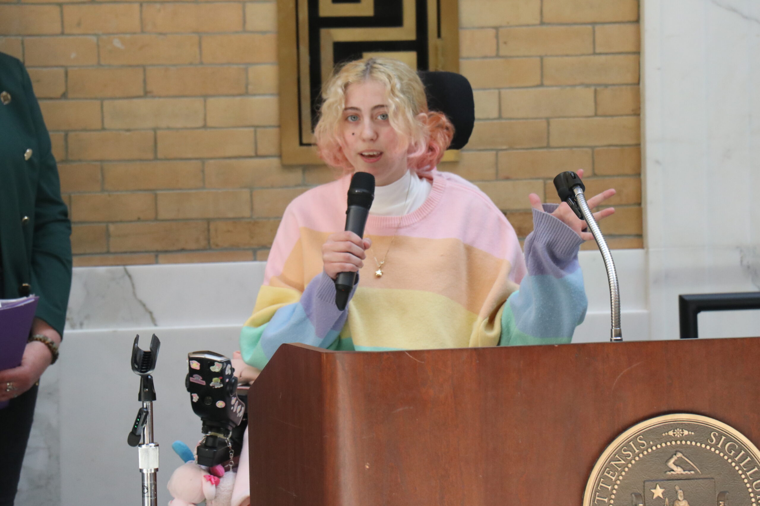 Stella McLauglin speaking at a podium holding a microphone