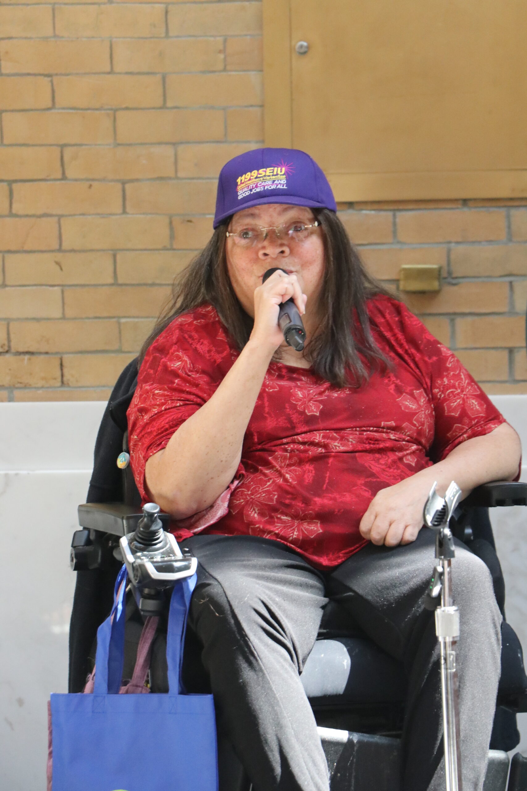 Nancy Garr-Colzie holding a microphone and speaking, wearing an SEIU 1199 hat