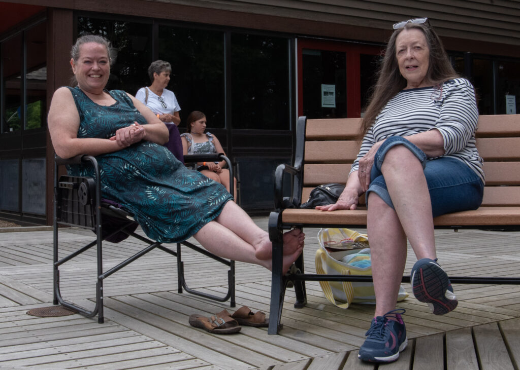 two women sitting overlooking pond