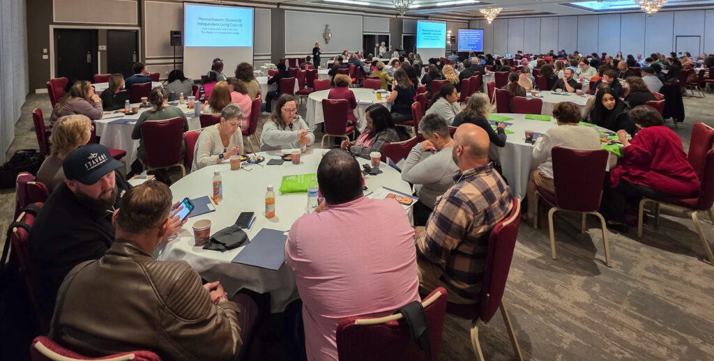 Room full of conference attendees sitting at round tables