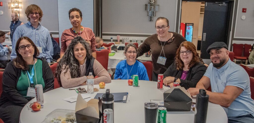 A group of people sitting at a table and smiling for a photo