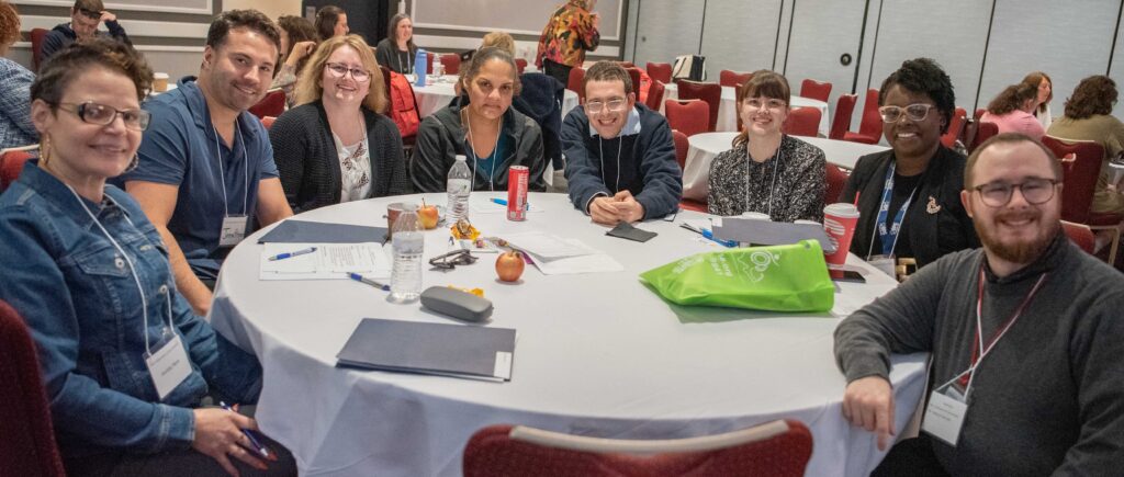 A group of people sitting at a table and smiling for a photo
